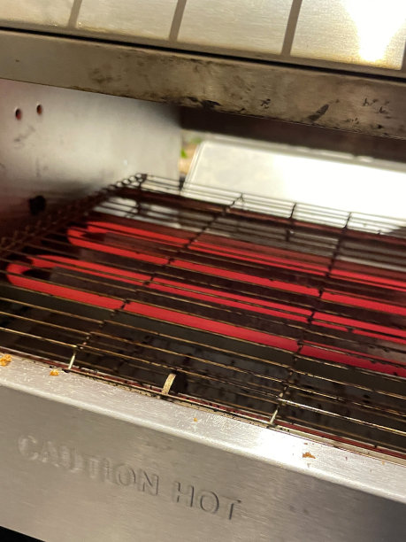 特写图像的红色加热元件在不锈钢商业输送烤面包机烤架，高架视图，重点在前景图片下载
