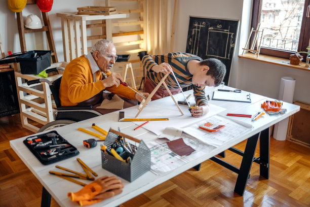 男孩在他的木工作坊里帮助坐轮椅的爷爷图片下载