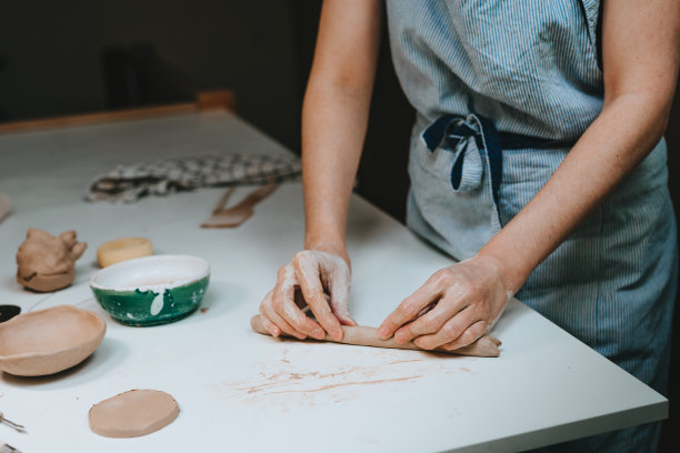 年轻的陶工在车间里摆弄陶土图片下载
