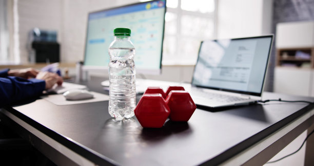 水瓶和哑铃放在工作的商人面前图片下载