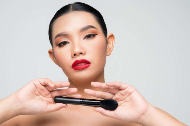 美丽的亚洲女人肖像手持化妆腮红刷图片下载