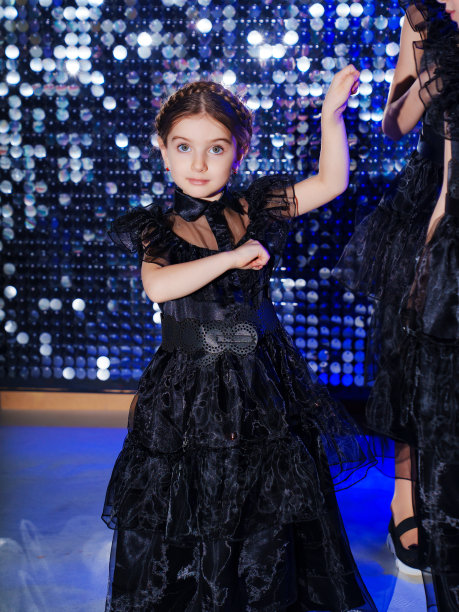 可爱的小女孩辫子在黑色长曲线连衣裙在迪斯科舞厅图片下载