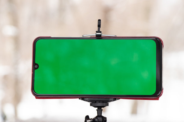 冬天，绿色屏幕的手机放在室外道路上的一个灵活的支架上图片下载