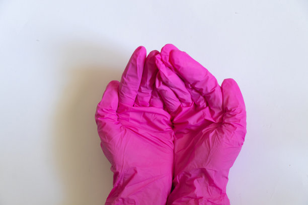 女性手戴白色背景的粉色医用手套图片下载