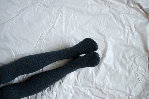 女性的腿在灰色温暖的紧身衣上的皱巴巴的背景图片下载