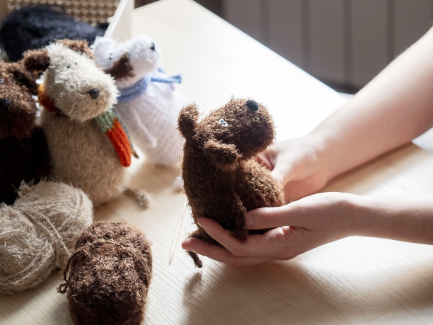 一个年轻女子手里的针织玩具。针织理念，手工制作，心灵健康的活动。图片下载