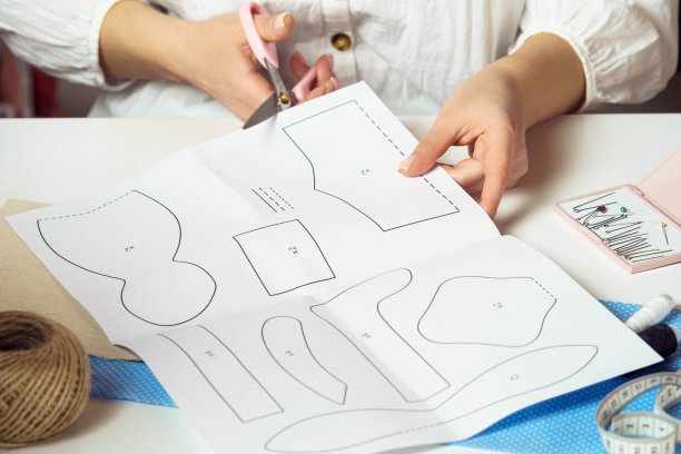 裁剪图片女设计师雇主手从纸上剪出数字图案，制作衣服和玩具图片下载