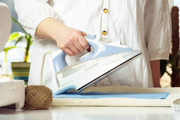 九分女装，白色衬衫熨烫，用熨斗烫出蓝色皱布放在桌上。裁缝准备布料图片下载