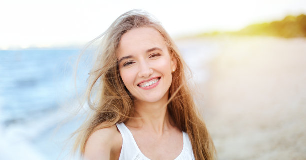 一个快乐的微笑的女人在自由的幸福幸福的海洋海滩上享受自然在旅行假期度假户外的肖像。透过白色模糊的花朵图片下载