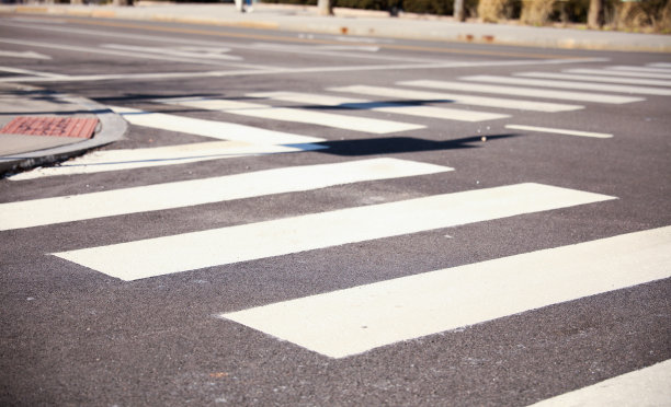 繁忙的现代城市街道上的白色人行横道，有行人标志和信号灯，在喧嚣的城市中为行人指明了一个安全的地方。图片下载