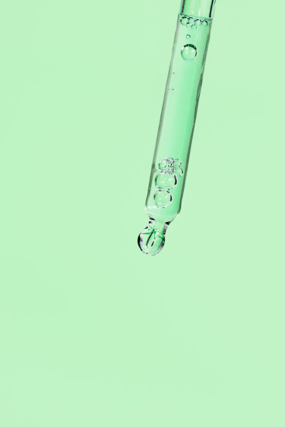 面部精华液，玻璃移液管，浅绿色背景。有气泡的液体凝胶或精油。时髦的抗衰老美容产品与透明质酸特写。复制空间，前视图图片下载