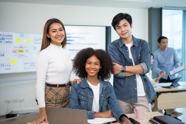 年轻的商人和一个美丽的亚洲女商人交叉双臂站在公司，摆出美丽的团队照片。图片下载