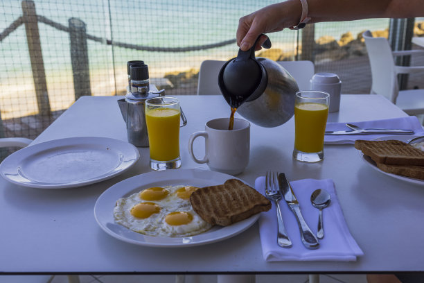 近距离观察倒咖啡在早餐期间在室外餐厅的杯子与大西洋的观点。阿鲁巴岛。图片下载