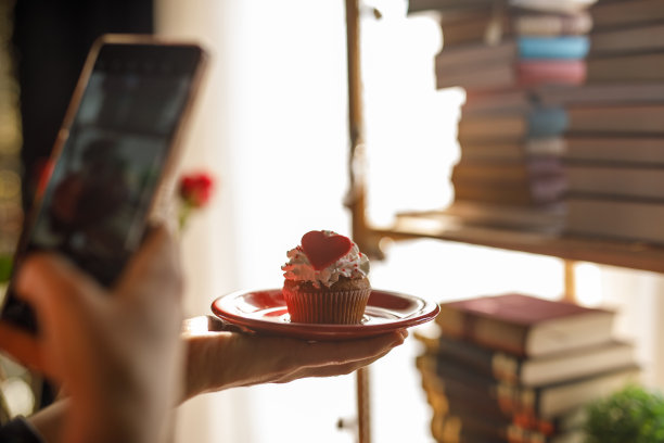 一名年轻女子正在拍摄美味的情人节主题纸杯蛋糕图片下载