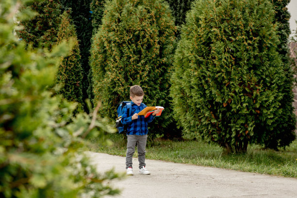 小一年级的孩子背着书包，从学校回家，看着抄写本图片下载