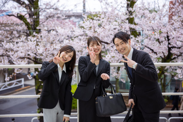 快乐的商务人士在樱花前做和平手势图片下载
