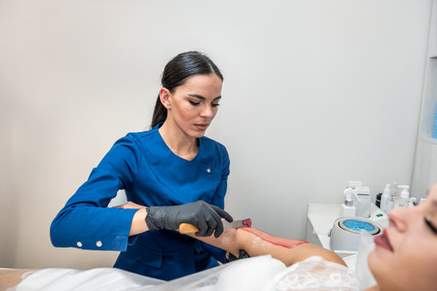 美容院美容师用热糖给女顾客打蜡。图片下载