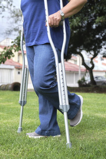 一个不知名的女人拄着拐杖在城市公园里行走。图片下载