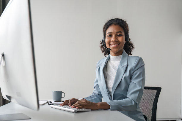 工作场所快乐微笑的女性客户支持电话接线员的肖像。在呼叫中心工作的微笑美丽的非洲裔美国妇女图片下载