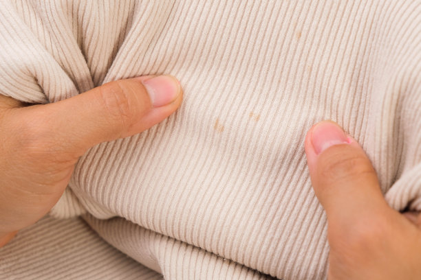 一个女人的特写，看着孩子不能洗的衬衫上的脏污渍。不满的年轻女子显示污渍的t恤。衣服的问题图片下载