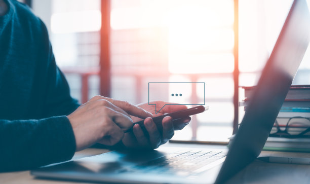 社交媒体短信的概念，男人使用智能手机短信，坐在桌子上与笔记本电脑在办公室温暖的早晨或晚上图片下载