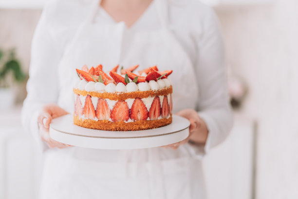 糖果师在白色制服拿着草莓慕斯蛋糕图片下载