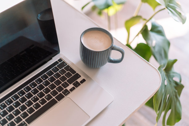 笔记本电脑和一杯咖啡放在怪物旁边的桌子上图片下载