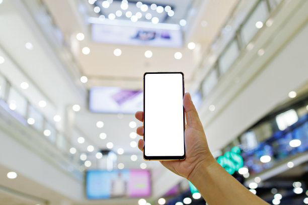 一个男子在购物中心拿着一个空白屏幕的智能手机的模型图片下载