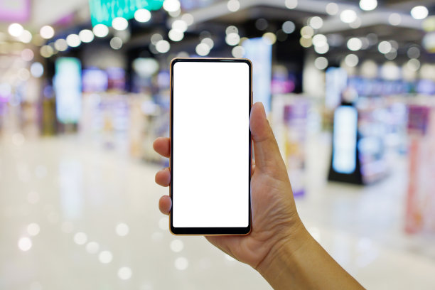 一个男子在购物中心拿着一个空白屏幕的智能手机的模型图片下载