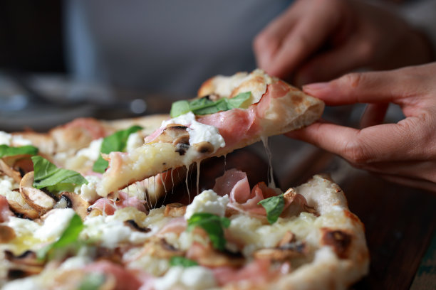 一个年轻的亚洲女人拿着一片新做的披萨图片下载