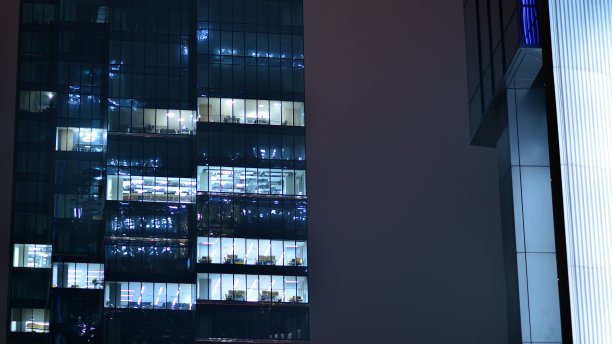 城市中现代化的办公大楼在夜晚。公司建筑的照明办公室视图。图片下载