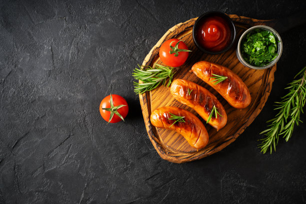 在船上烧烤和烧烤香肠，黑色背景上有酱汁、西红柿和迷迭香图片下载