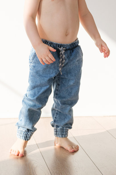 穿着松紧带牛仔裤的赤脚男孩站在地板上图片下载