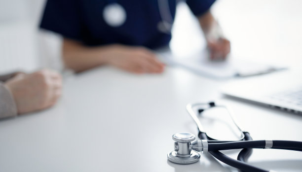 听诊器躺在平板电脑前，医生和病人在后台。医学、保健概念图片下载