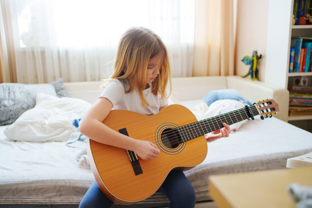 可爱的小女孩在学弹吉他。图片下载