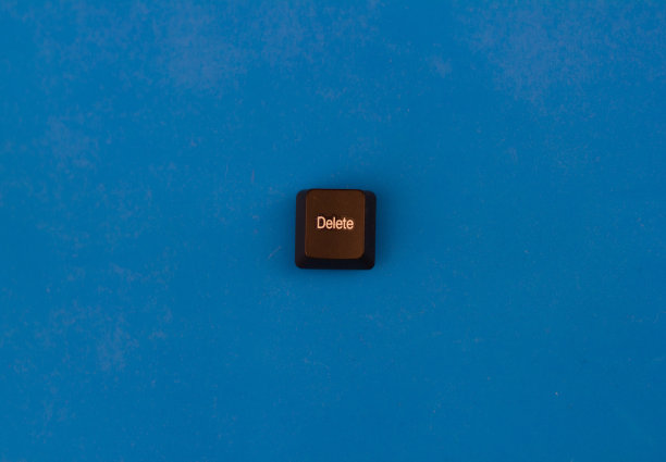 从隔离在蓝色背景上的计算机键盘上删除按钮。一个带有“删除”字样的黑色按钮位于蓝色背景上，与键盘分开。图片下载