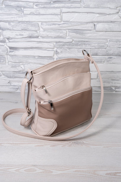 女式米色包配长腰带。车身由人造皮革制成。灰色和黑色的背景。图片下载