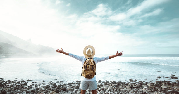 快乐的男人，张开双臂站在外面-快乐的旅行者，背包享受夏日旅行-成功人士，幸福和旅行的生活方式概念图片下载