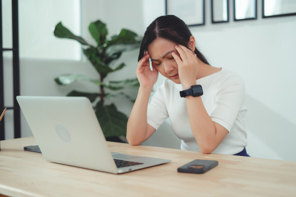 亚洲女性坐在家里头疼。图片下载