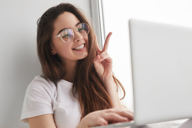 微笑的女士在家里的在线课程中显示V手势图片下载