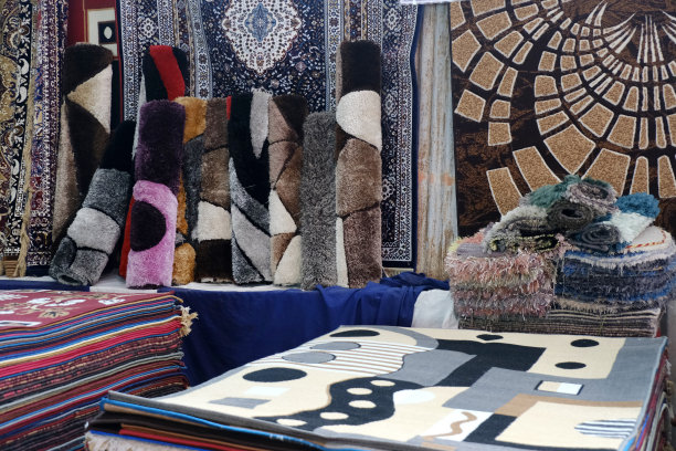 堆叠的彩色地毯在地毯店，地毯品种选择卷起来的地毯店店。图片下载