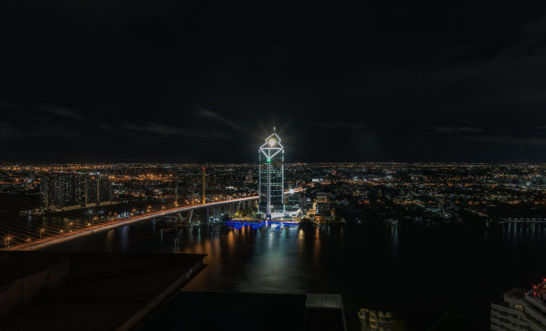 美丽的摩天大楼和大桥横跨曼谷城的湄南河，夜间灯光明亮。图片下载