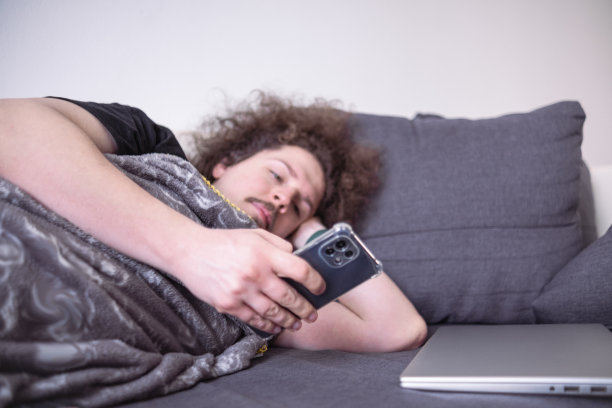 在电话上浏览新闻，躺在沙发上图片下载