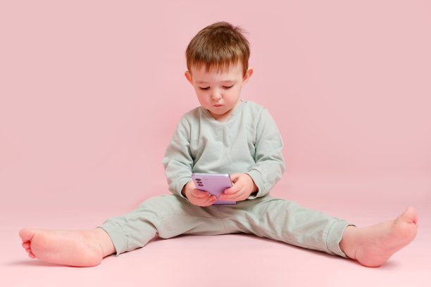 快乐的蹒跚学步的婴儿与手机工作室粉红色的背景。小男孩手里拿着智能手机。孩子一岁八个月，身高正常图片下载