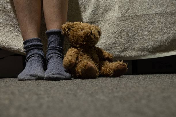穿着袜子的女性脚和房间地板上的棕色泰迪熊图片下载