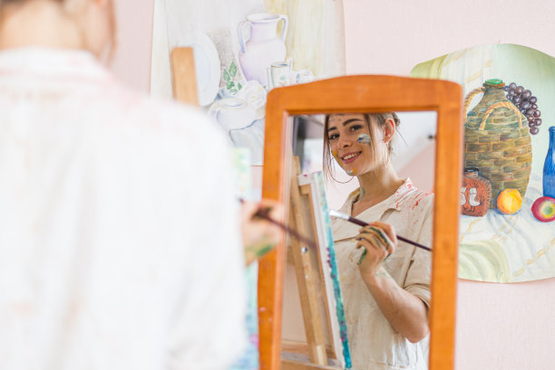 积极漂亮的年轻女孩正在画画，对着镜子微笑图片下载