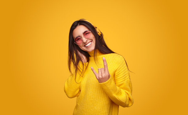 欢快的年轻民族女士听音乐，显示号角标志图片下载