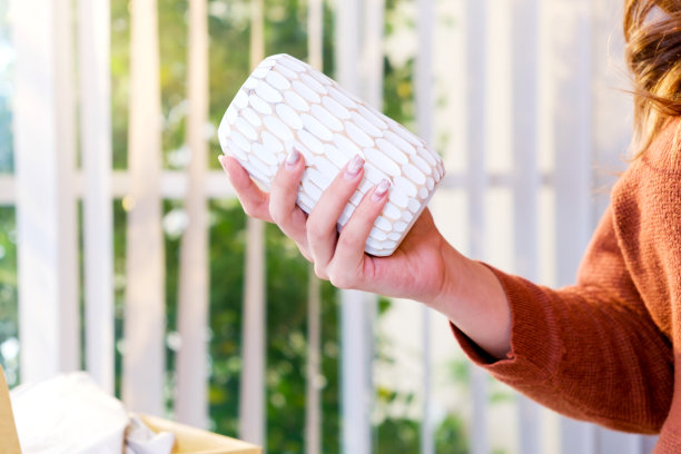 近距离的手，一个亚洲美女拿着花瓶产品出售在线直播在家里。年轻有吸引力的女孩向客户展示商品细节。网上购物的概念。图片下载