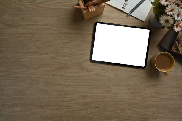 平铺，俯视图的数字平板电脑，咖啡杯，记事本和笔记本电脑在木桌上。广告文本信息的空显示。图片下载