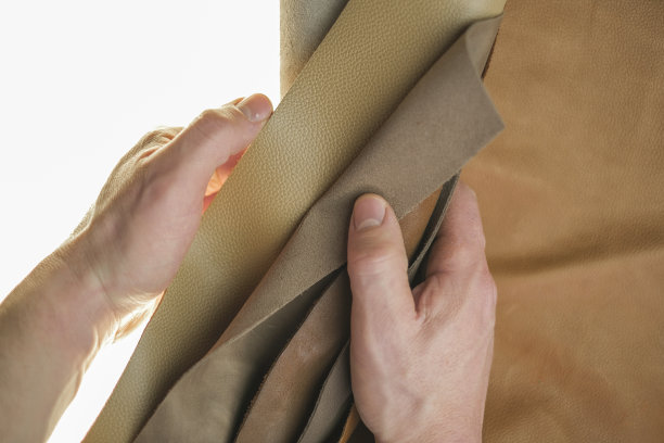 皮革件设置在男性手中的白色背景。皮革材质的选择。真皮品种。棕色真皮品种。图片下载